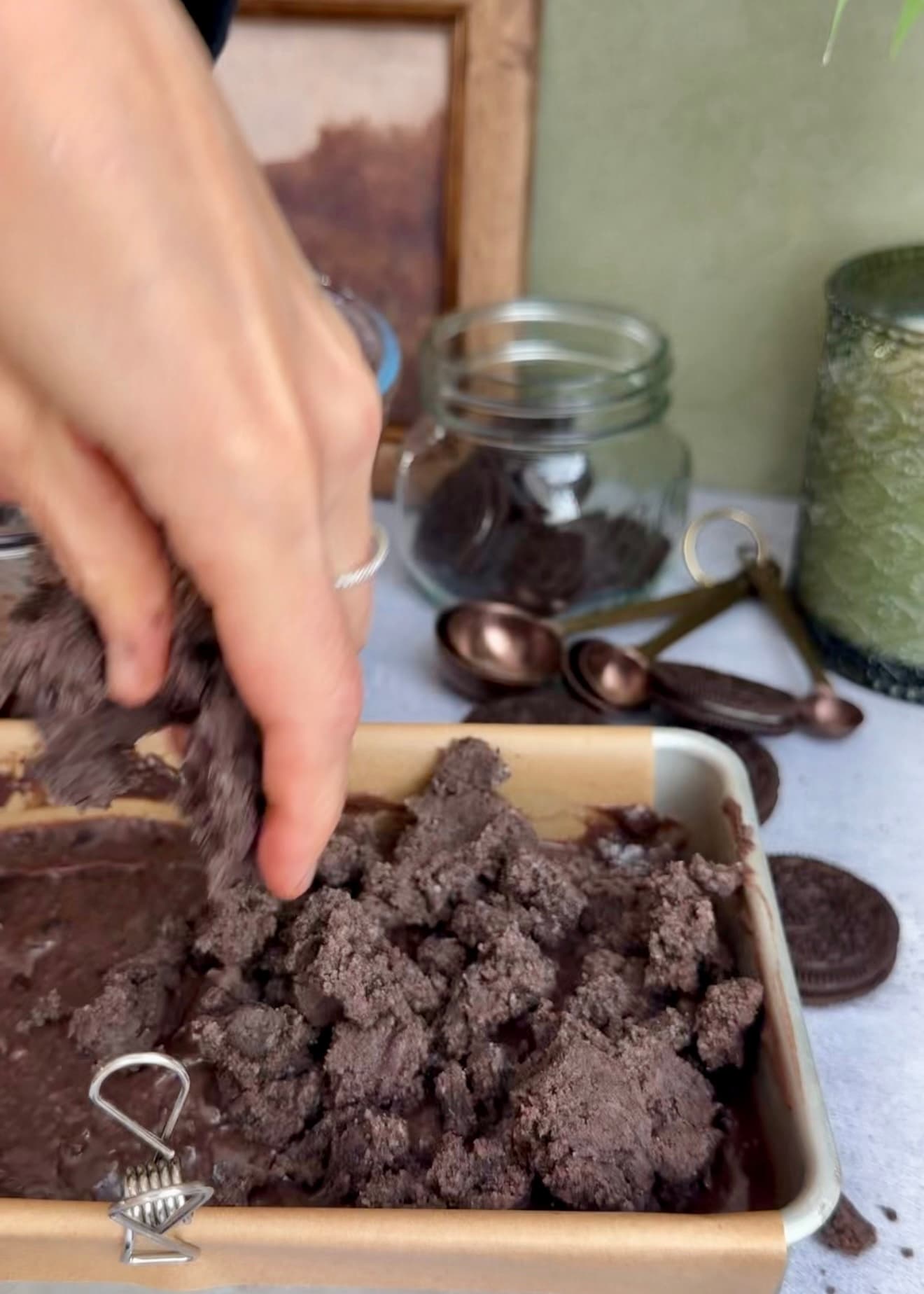 A hand scattering streusel over the top batter layer