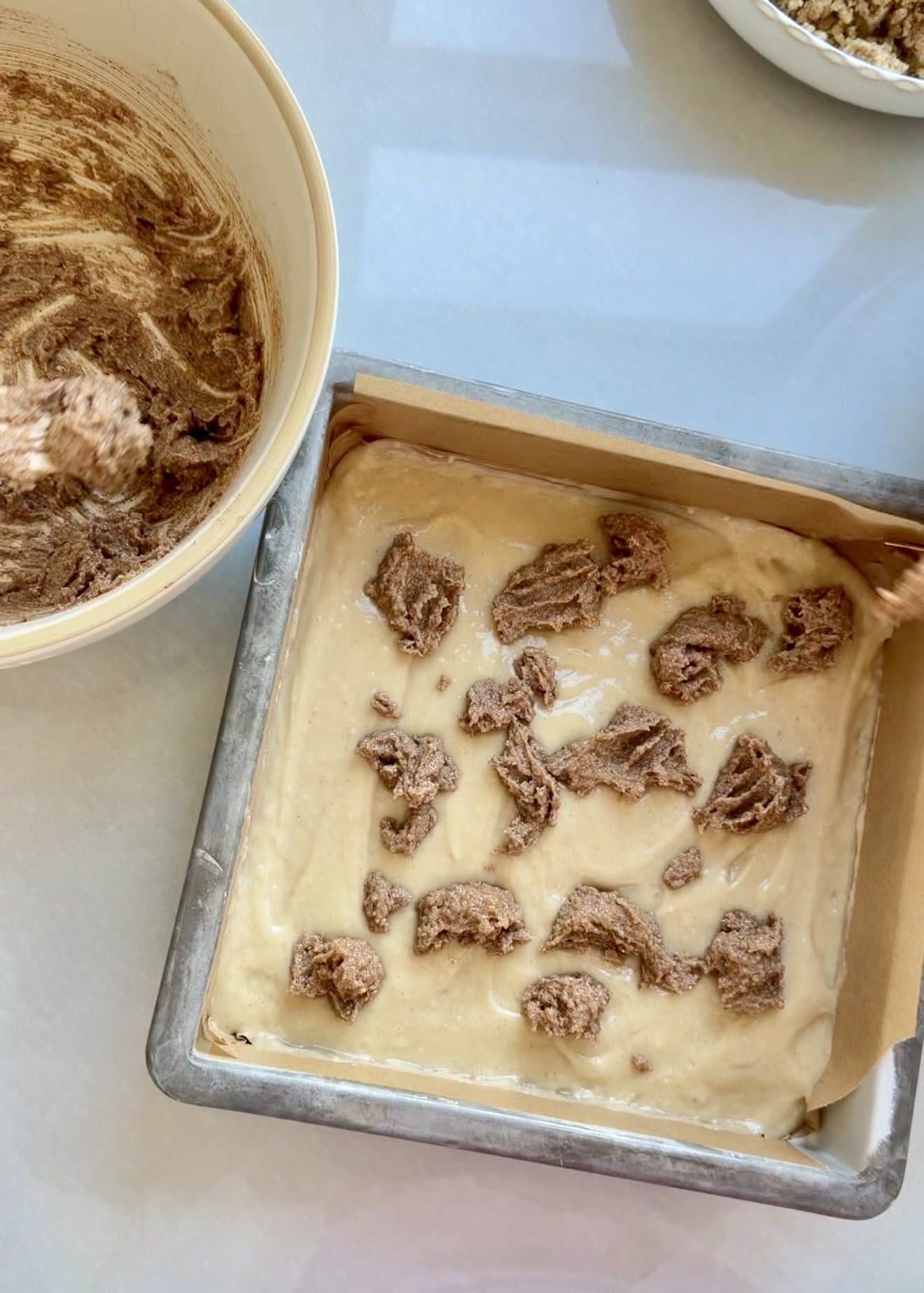 Spoonfuls of cinnamon swirl paste dotted over coffee cake batter