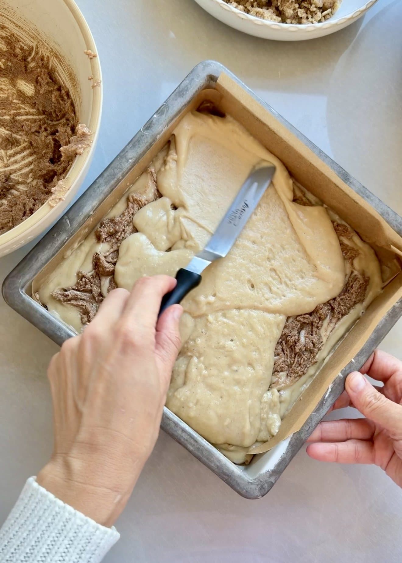 Remaining vanilla coffee cake batter being spread over the cinnamon swirl