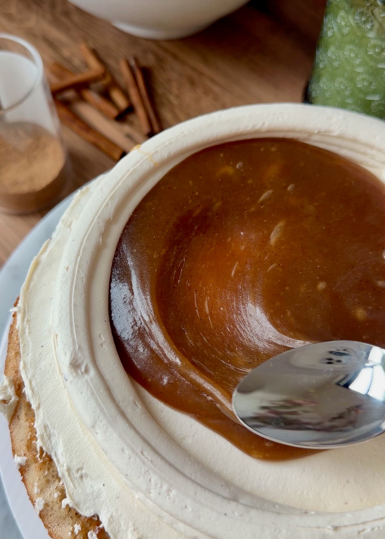 Thick cinnamon filling being spread inside the frosting dam
