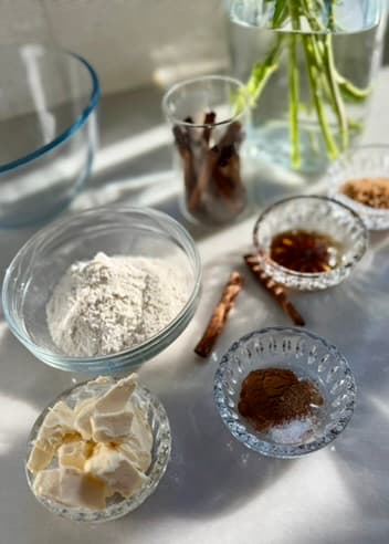 Flour, butter, cinnamon and vanilla arranged beside a mixing bowl