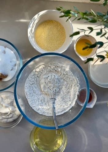 Measured flour, cornmeal and wet ingredients around a mixing bowl