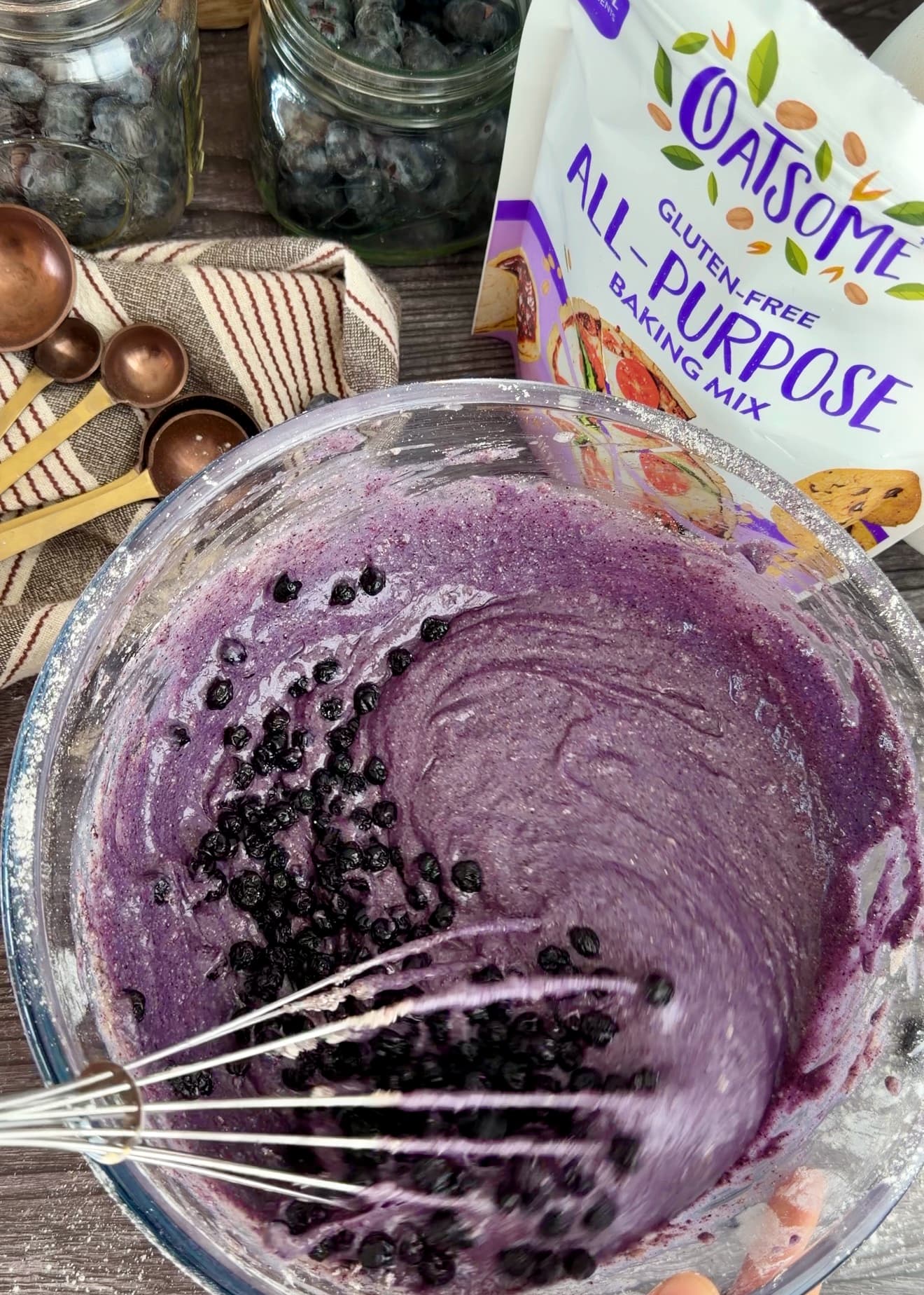 Dried blueberries scattered over purple batter in a bowl