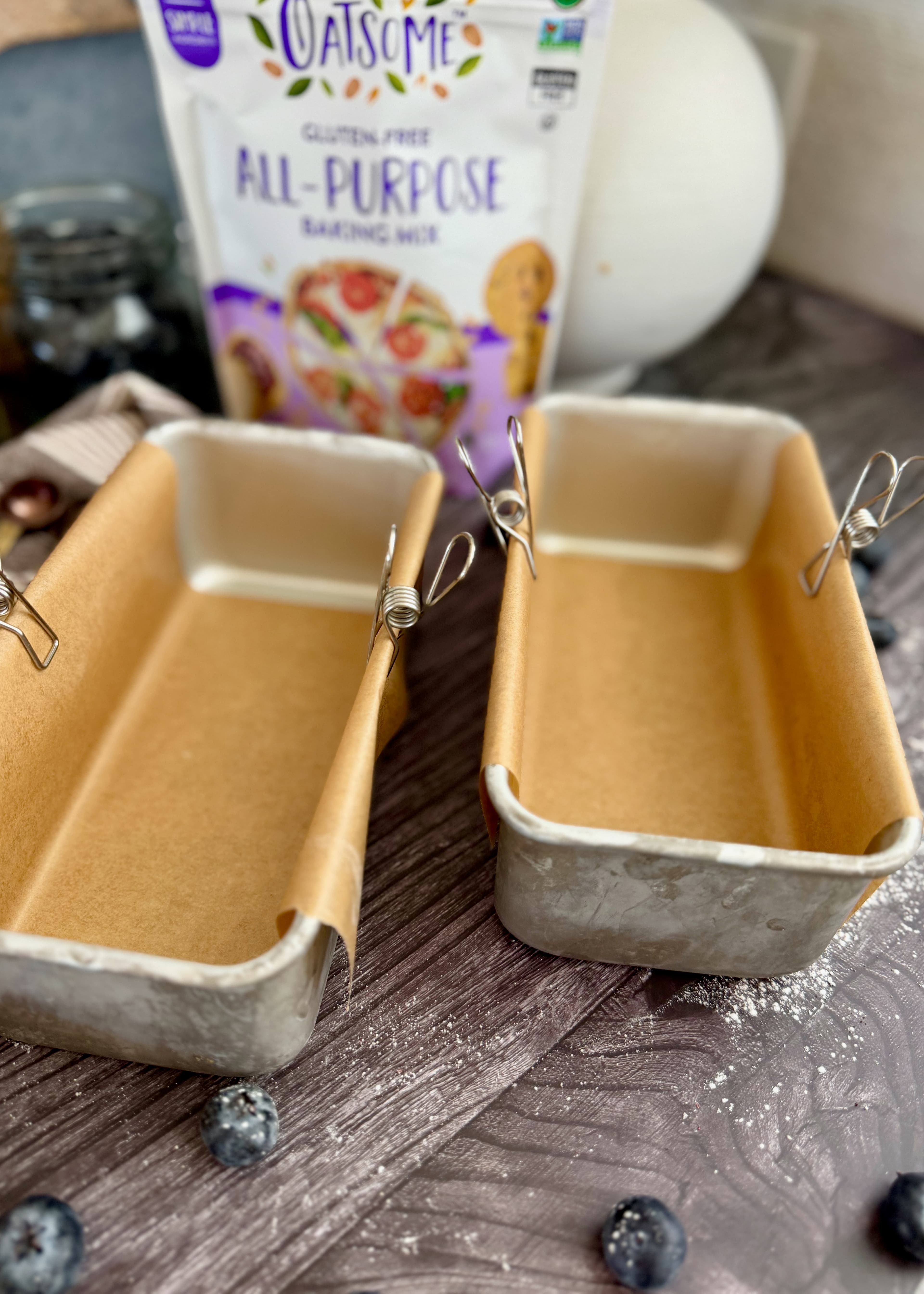 Two metal mini loaf pans lined with parchment and held with clips
