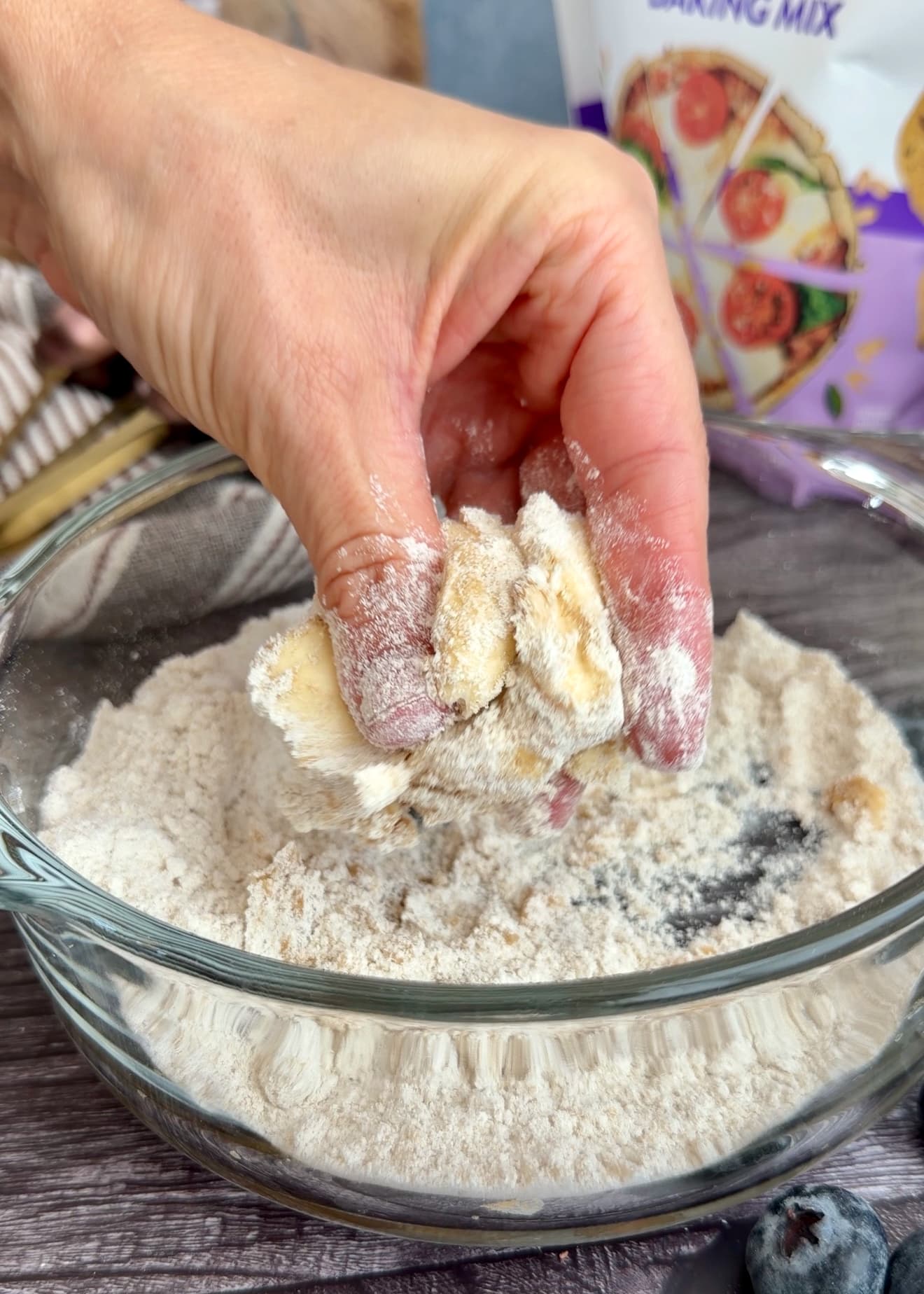 Fingers working butter into the dry crumble ingredients in a bowl