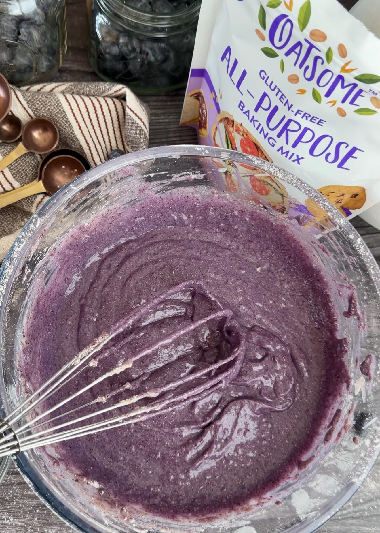 Purple blueberry batter with a whisk resting in a glass bowl