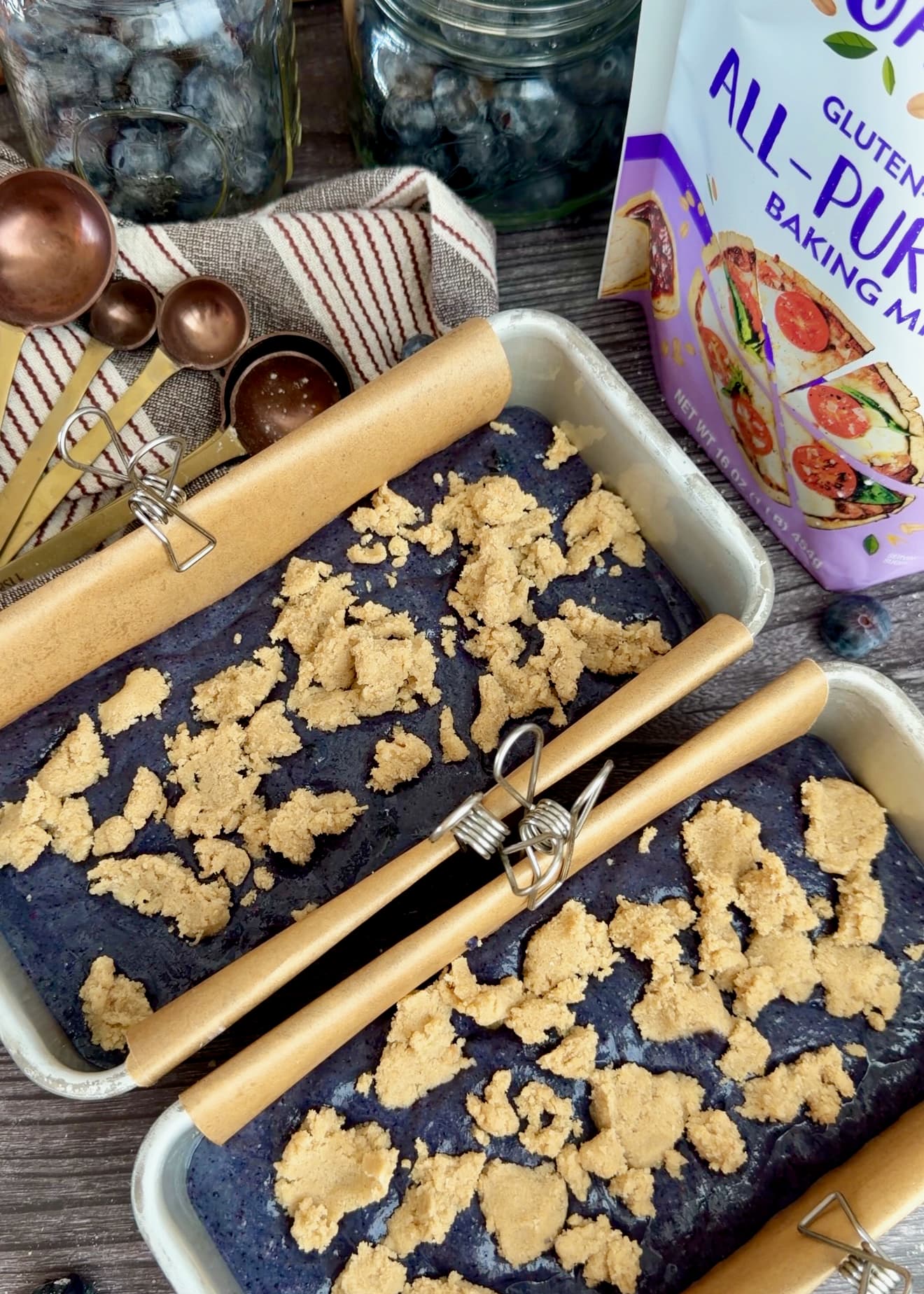 Two pans of blueberry batter topped with pale crumble