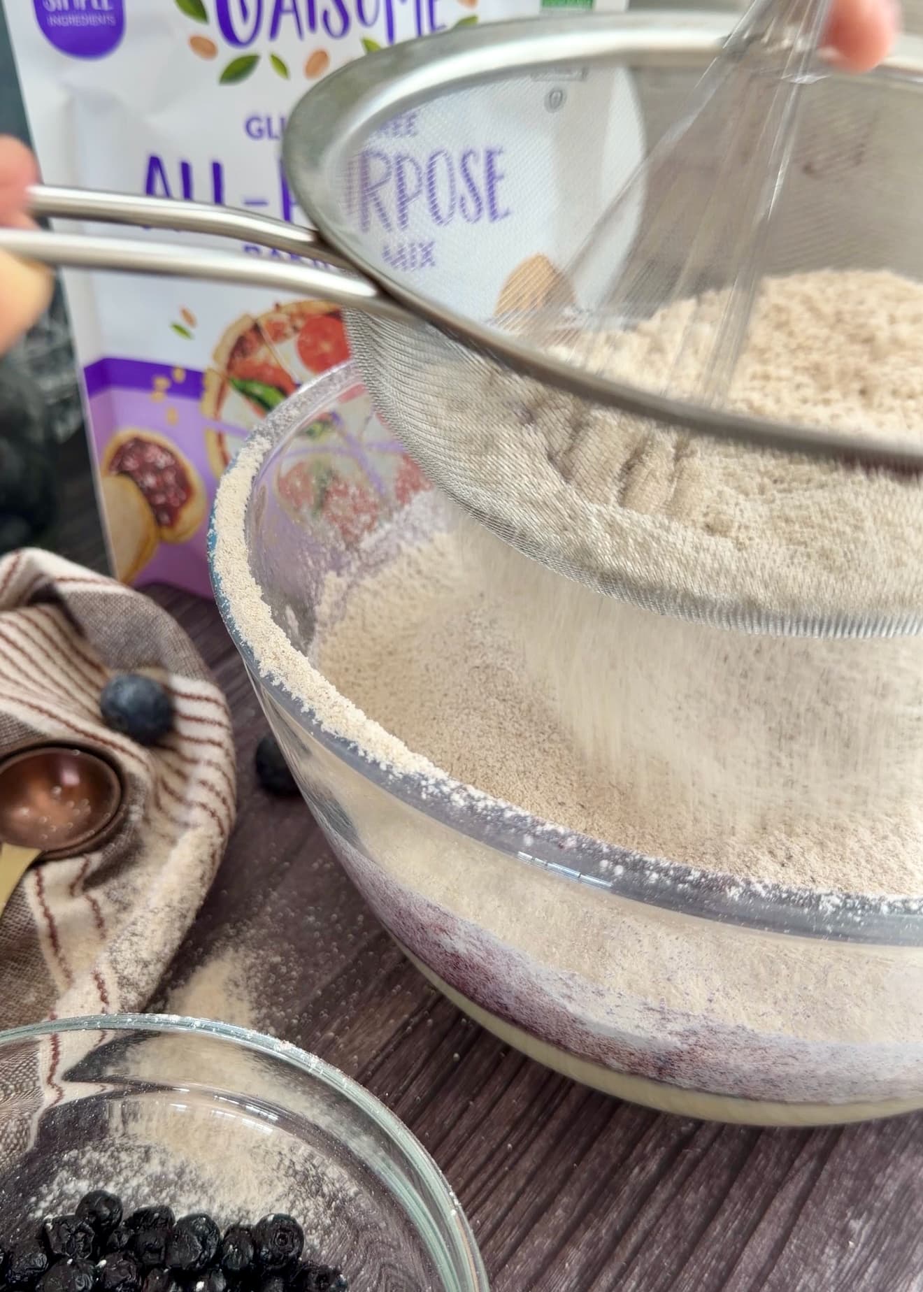 A fine mesh sieve holding dry ingredients above the mixing bowl