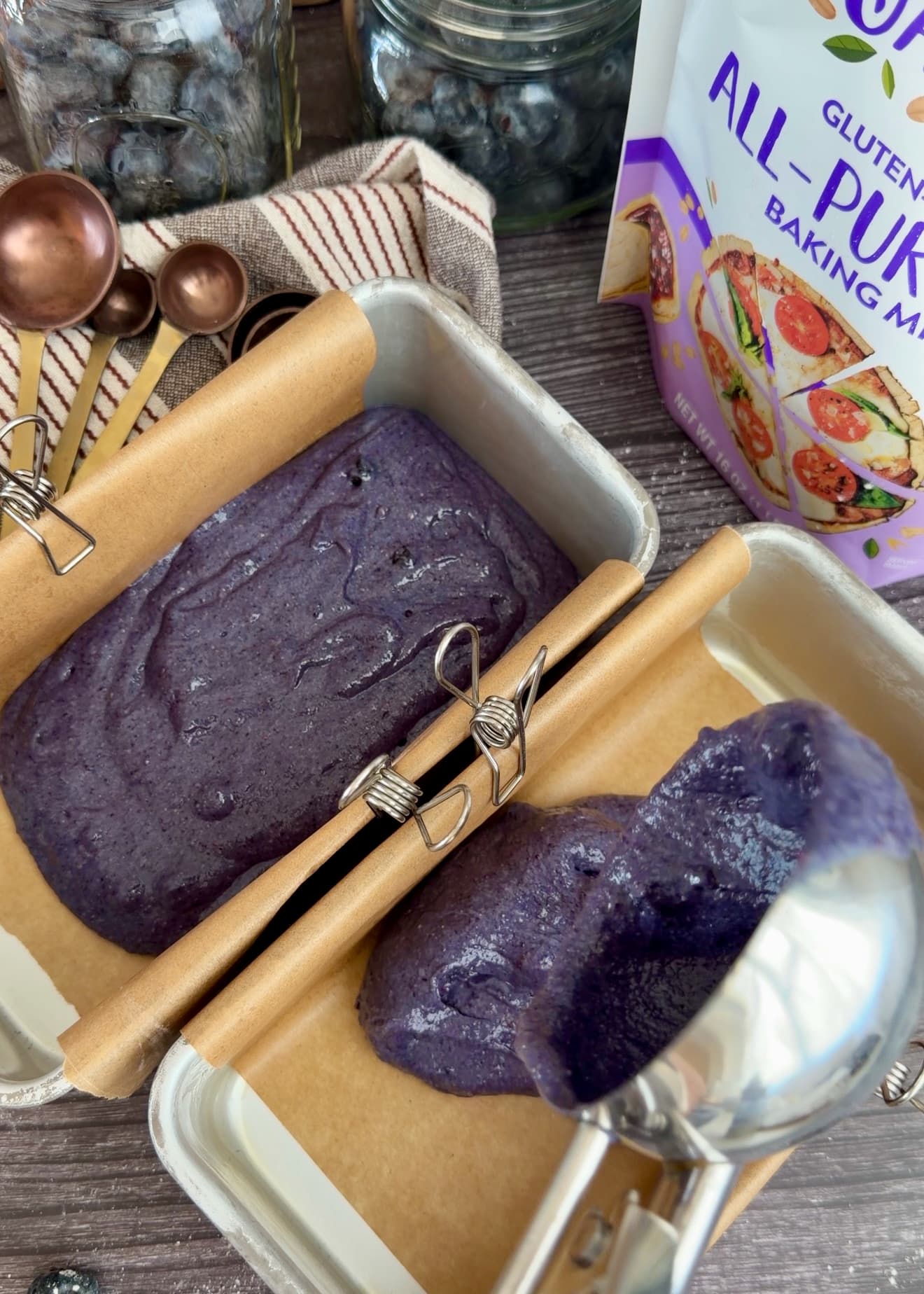 Purple batter spread across the bottom of a lined mini loaf pan