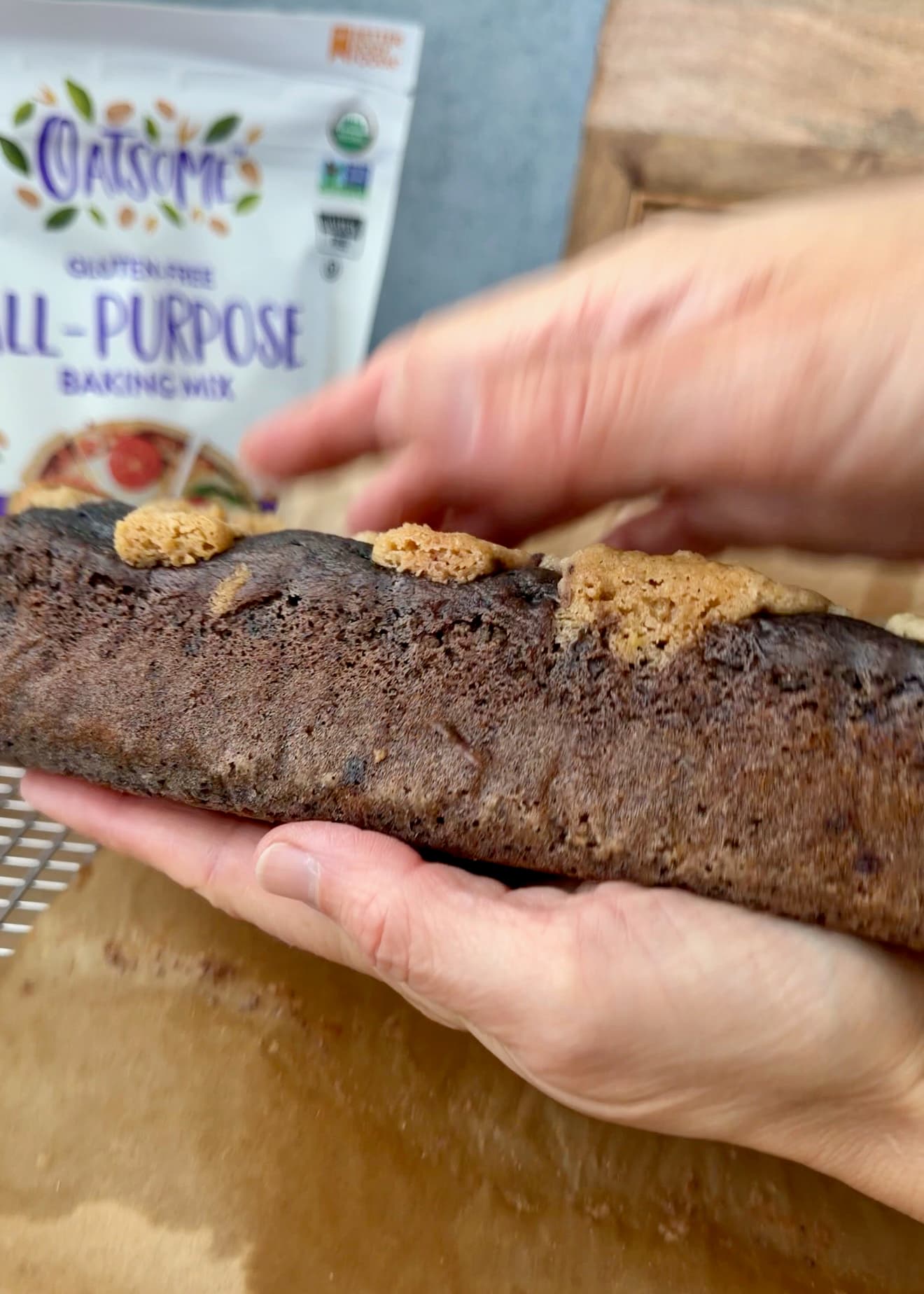Hands supporting an unwrapped blueberry loaf above its parchment