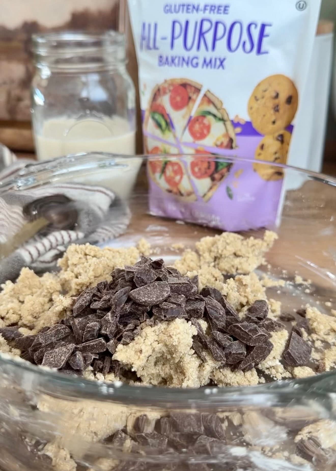 Chocolate pieces added on top of pale cookie streusel in a bowl