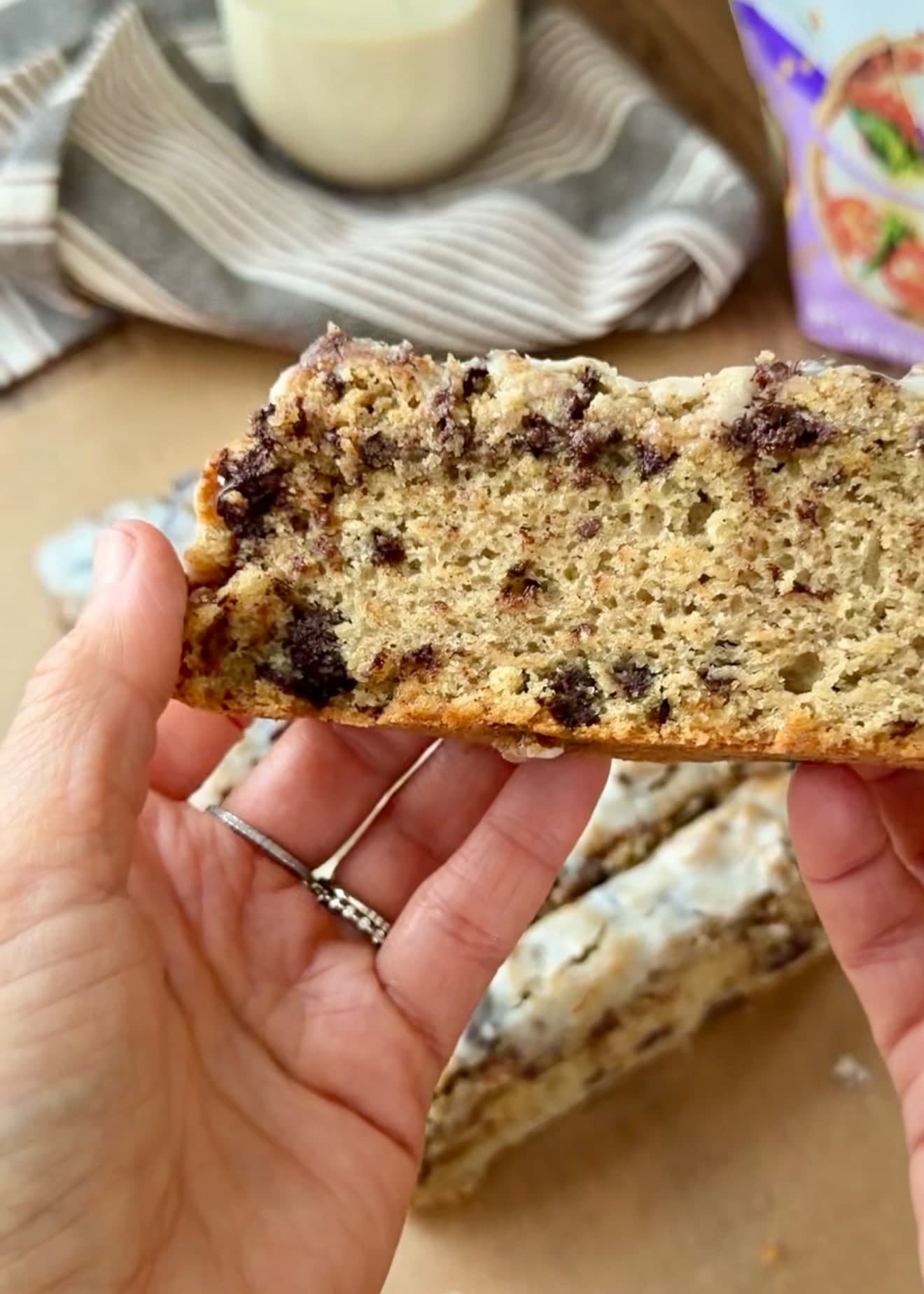 A slice held up to show its open crumb and chocolate pieces