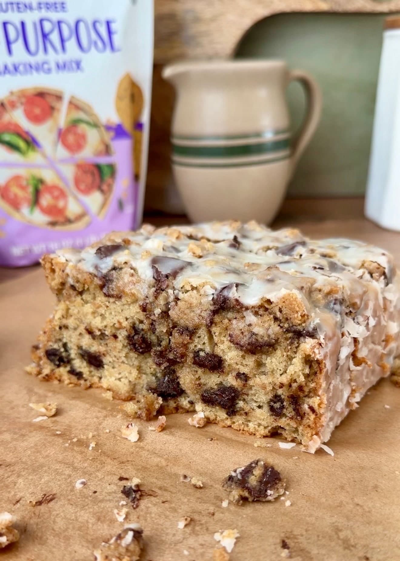 A cut glazed chocolate chip loaf showing its crumb on parchment