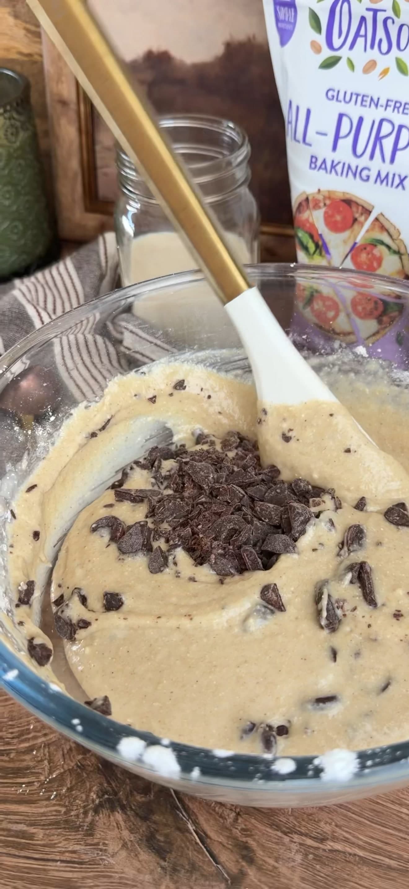 A spatula folding chopped chocolate through pale batter