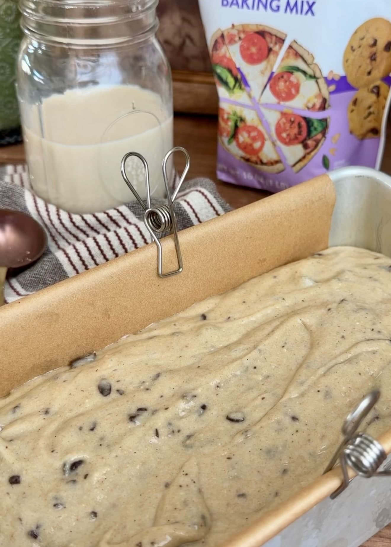 Chocolate chip batter spread evenly in a parchment-lined loaf pan