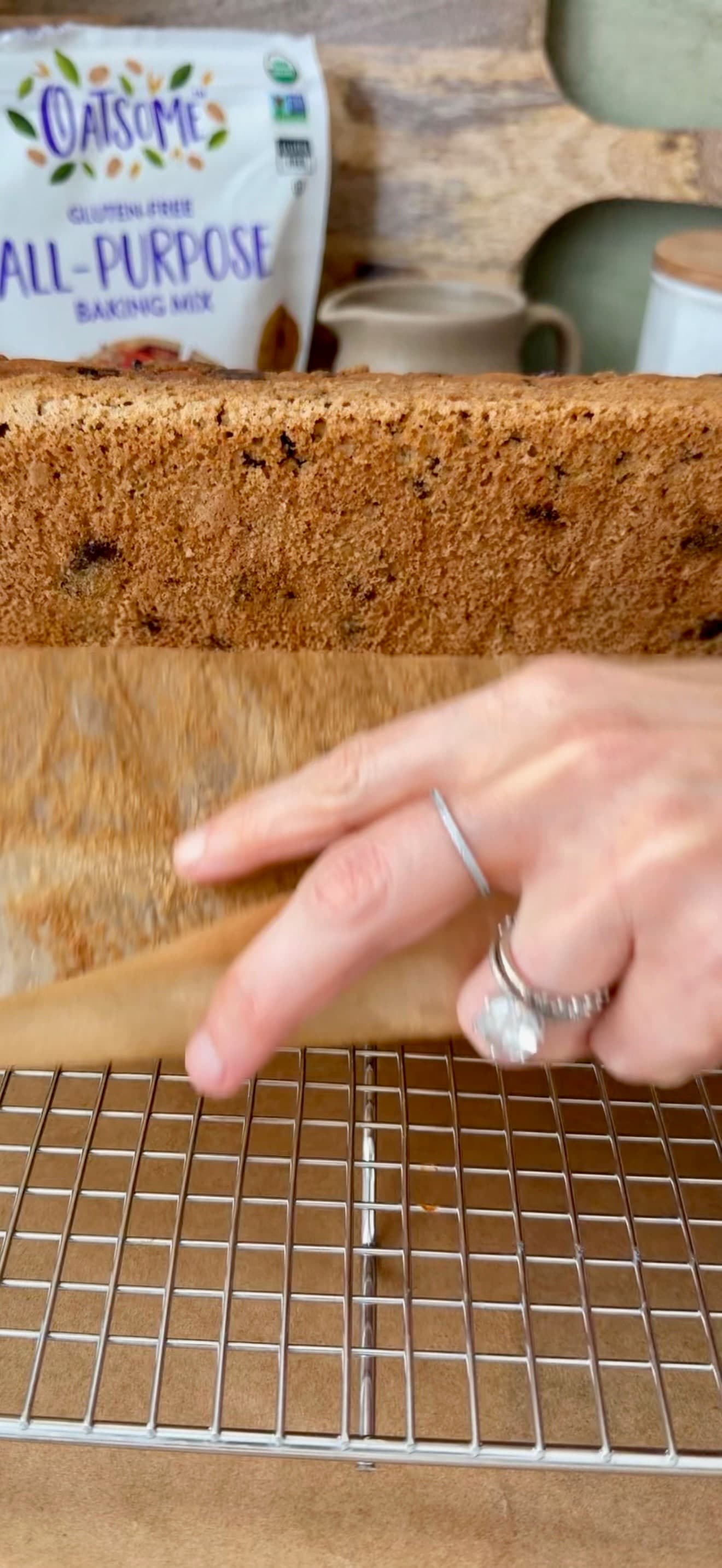 A hand peeling parchment from the base of the loaf while it rests on its side