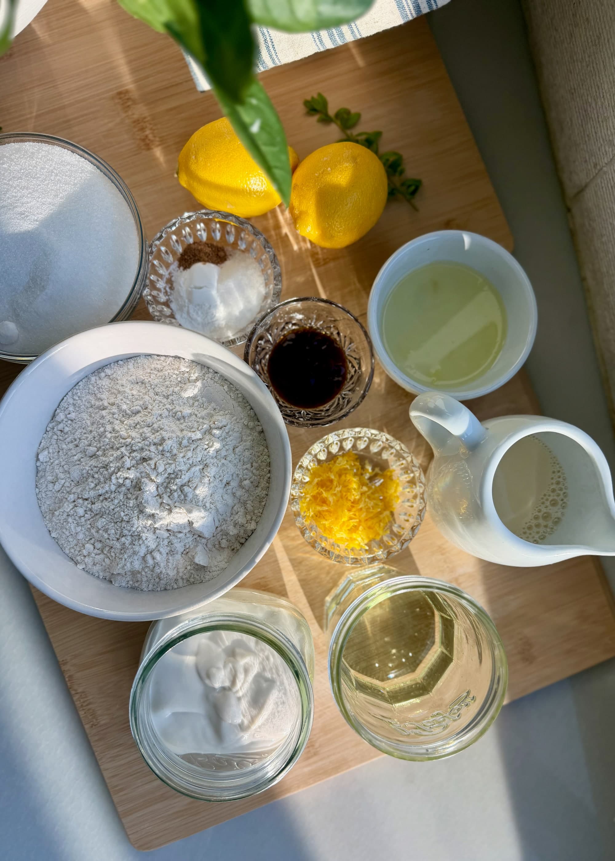 Overhead view of flour, sugar, yogurt, milk, oil, lemon zest, and vanilla bean paste