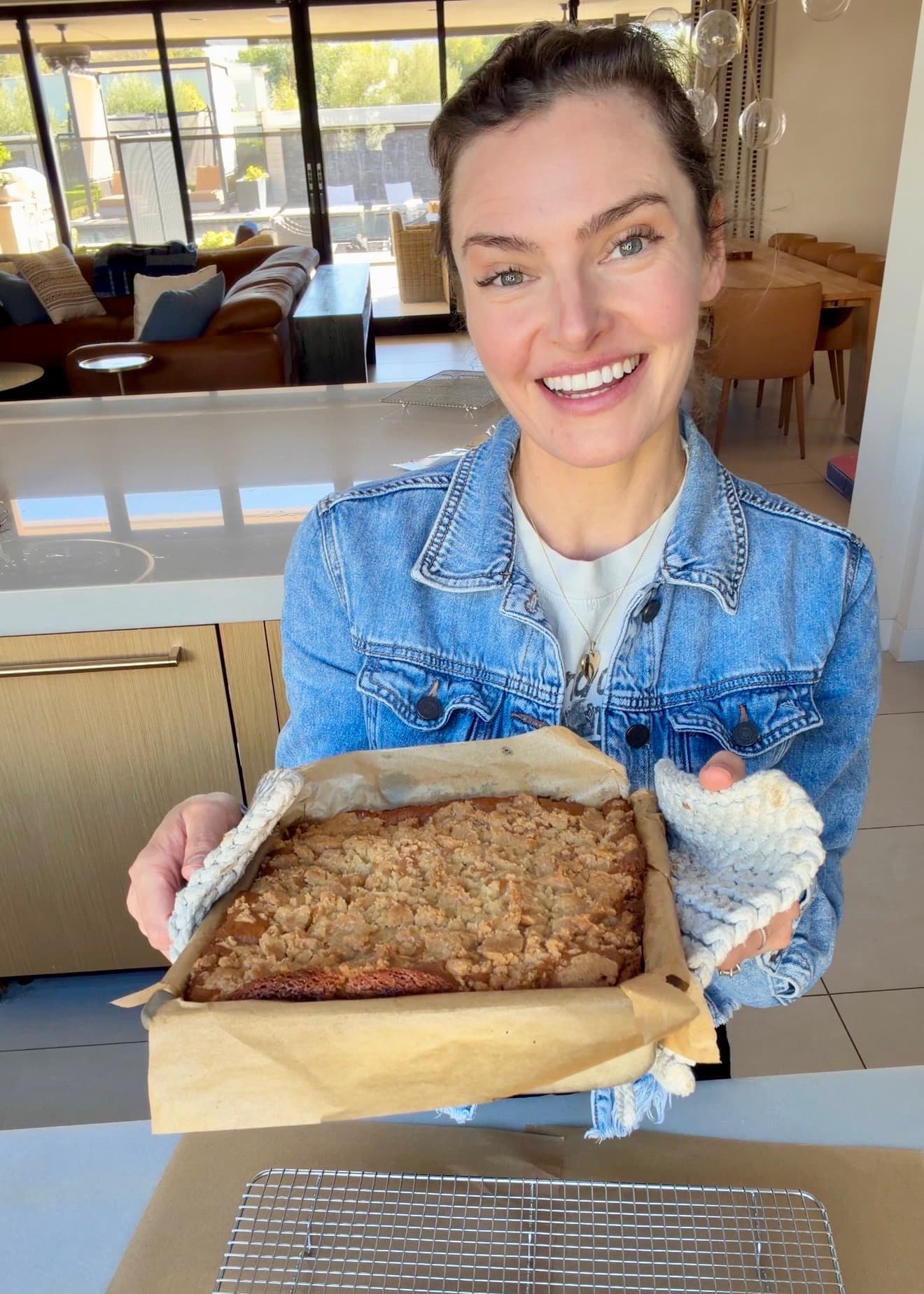 Angela holding the baked coffee cake in its parchment-lined pan