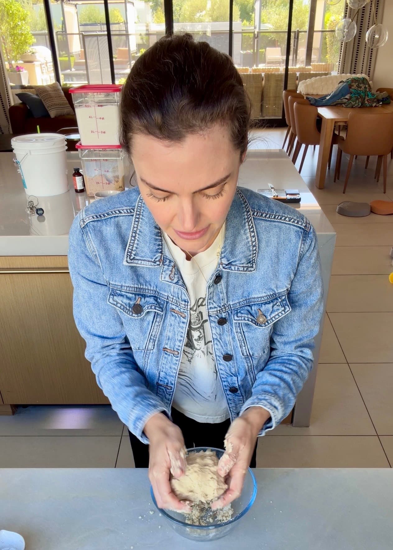 Hands holding the crumble together as a ball above a glass bowl
