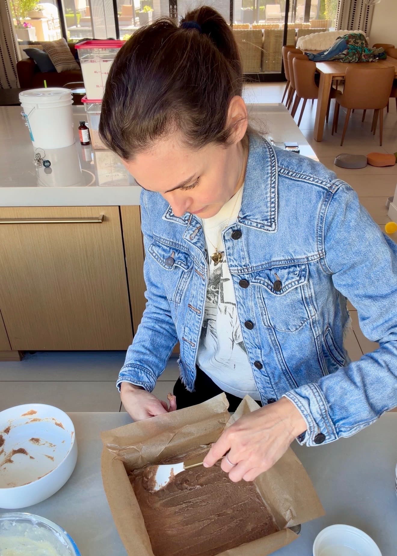 An even brown cinnamon layer being smoothed toward the edge of the pan