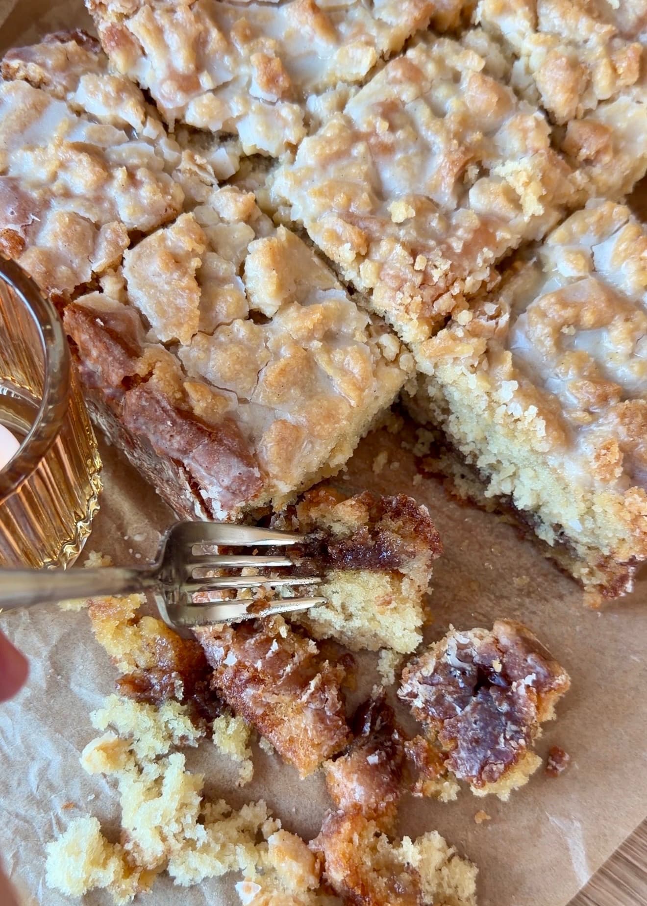A fork beside a piece of maple cake with cinnamon caramelized near the bottom