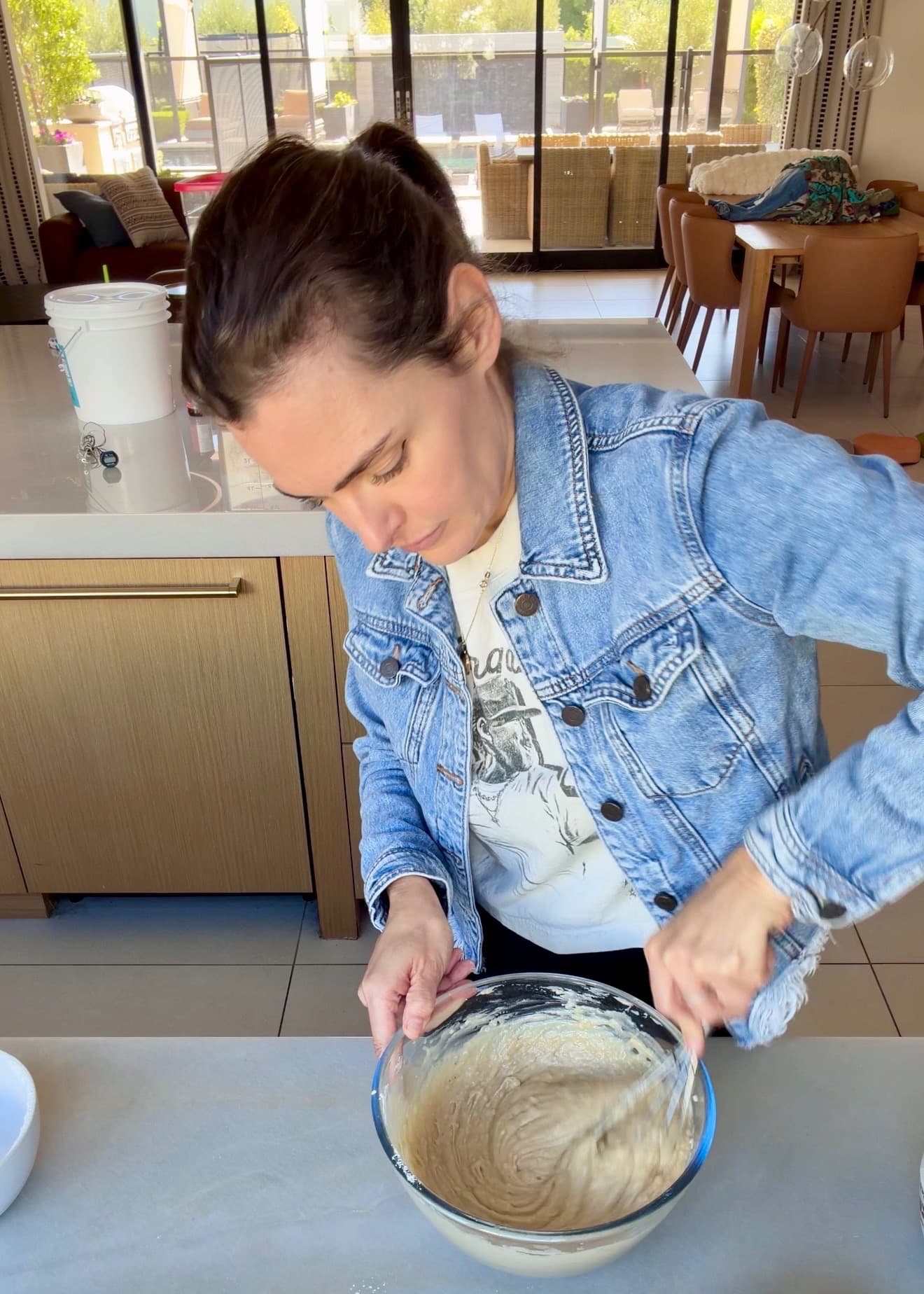 Angela stirring thick cake batter in a glass bowl