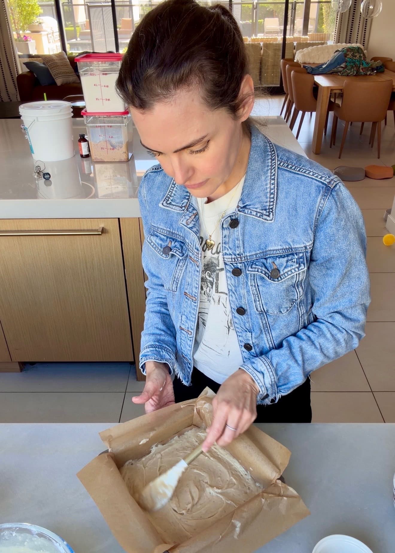 A spatula smoothing the base layer of cake batter into the corners