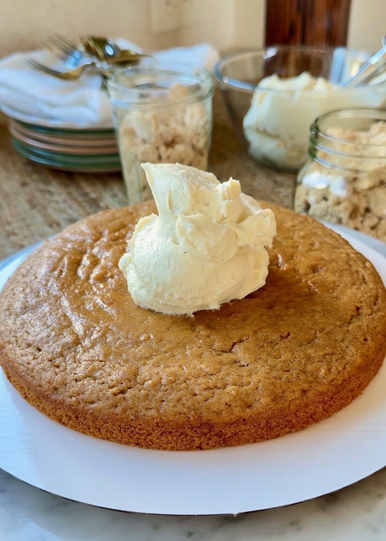 Vanilla buttercream spread over an oatmeal cake layer during assembly