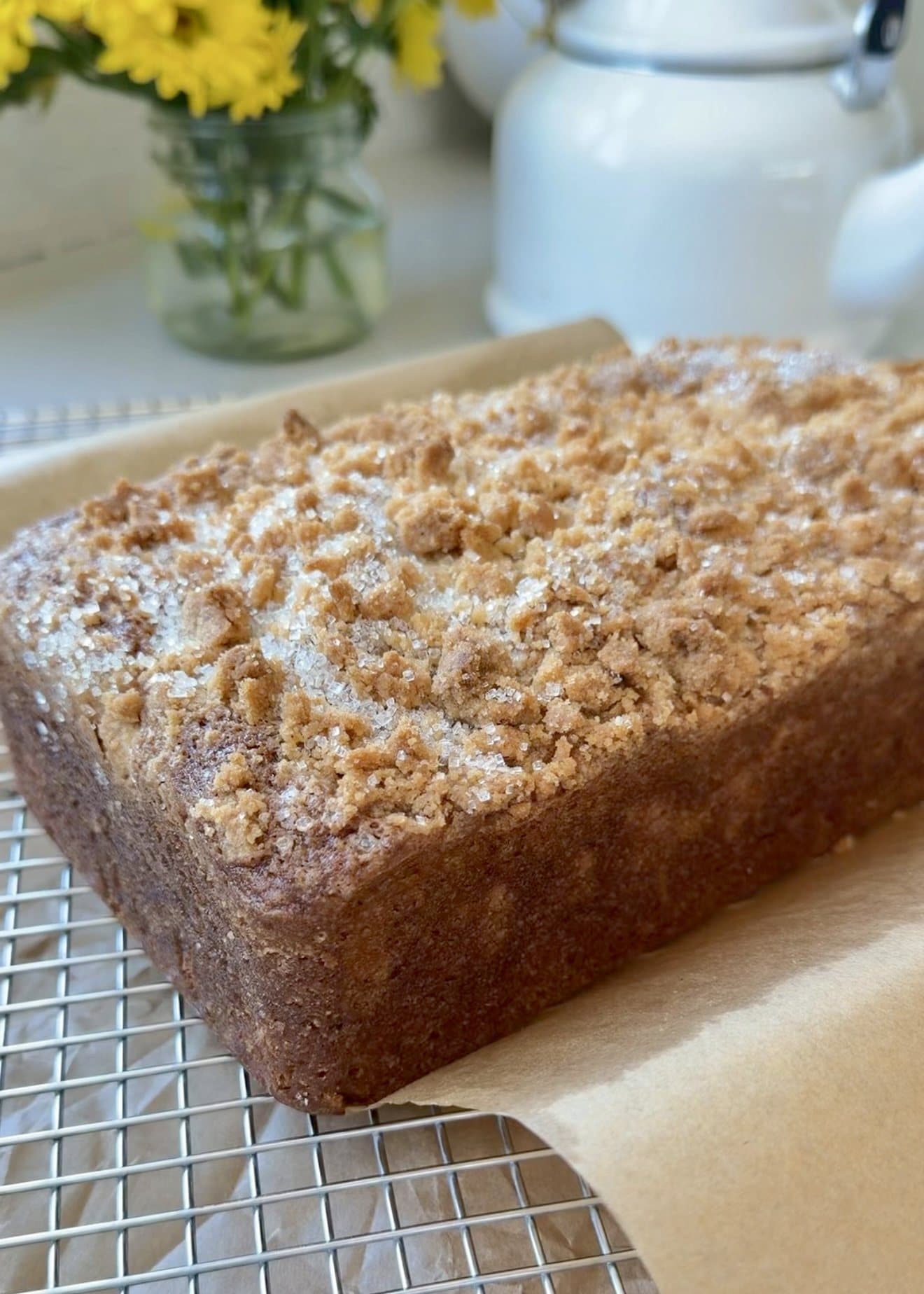 A golden streusel-topped loaf cooling on parchment on a wire rack