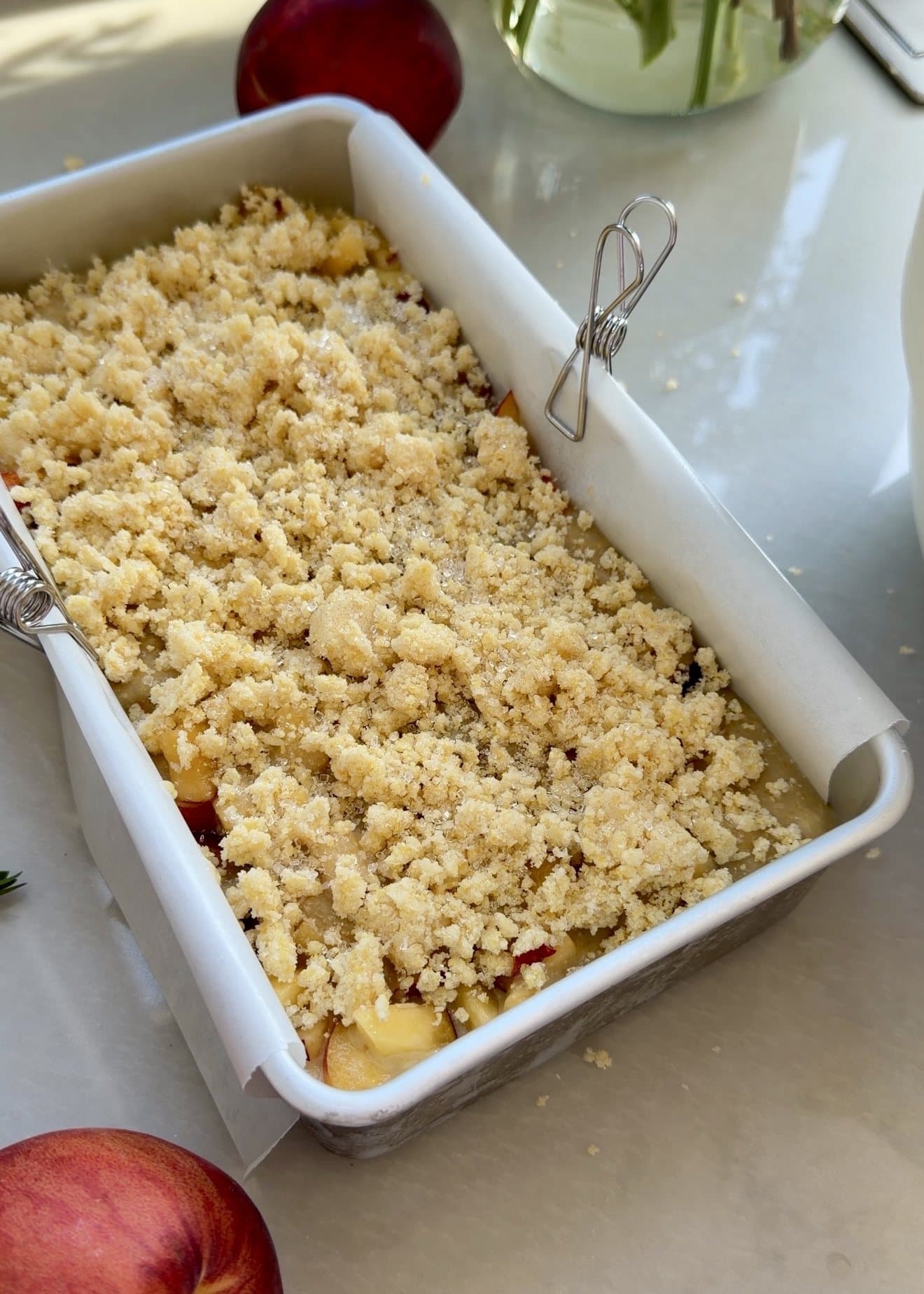 A lined loaf pan covered with pale golden cornbread streusel