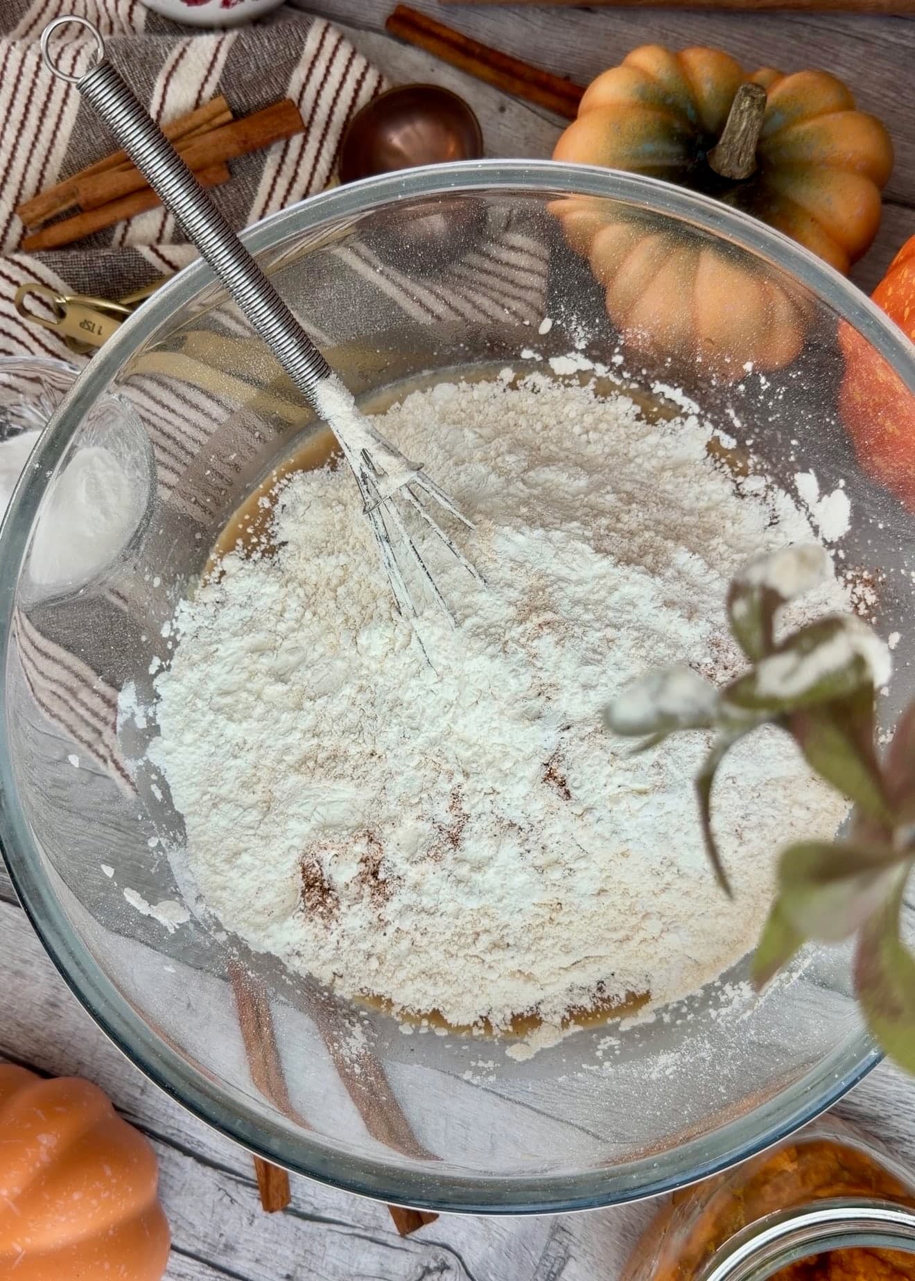 Flour and dry ingredients covering the wet mixture around a whisk