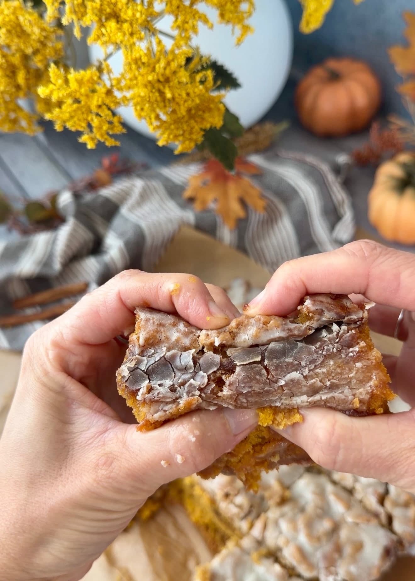 Hands pulling apart a glazed piece of pumpkin cake