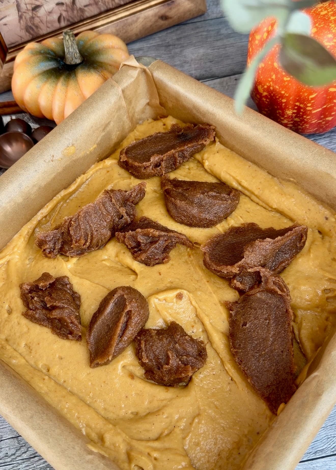 Separate spoonfuls of brown cinnamon paste on the pumpkin batter