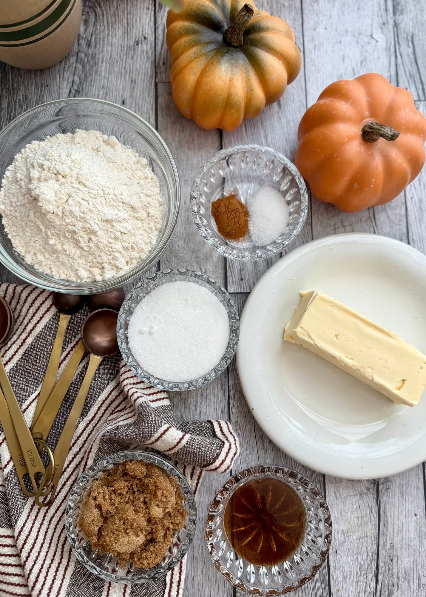 Measured crumble ingredients arranged beside butter and decorative pumpkins