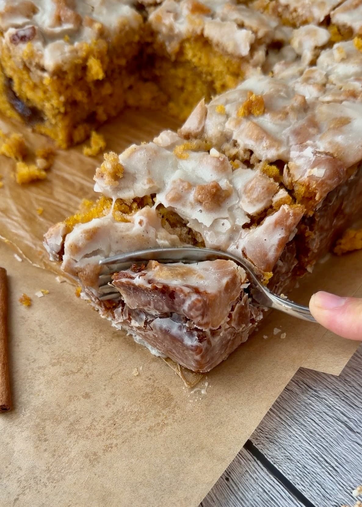 A fork cutting into the caramelized corner of a glazed cake slice