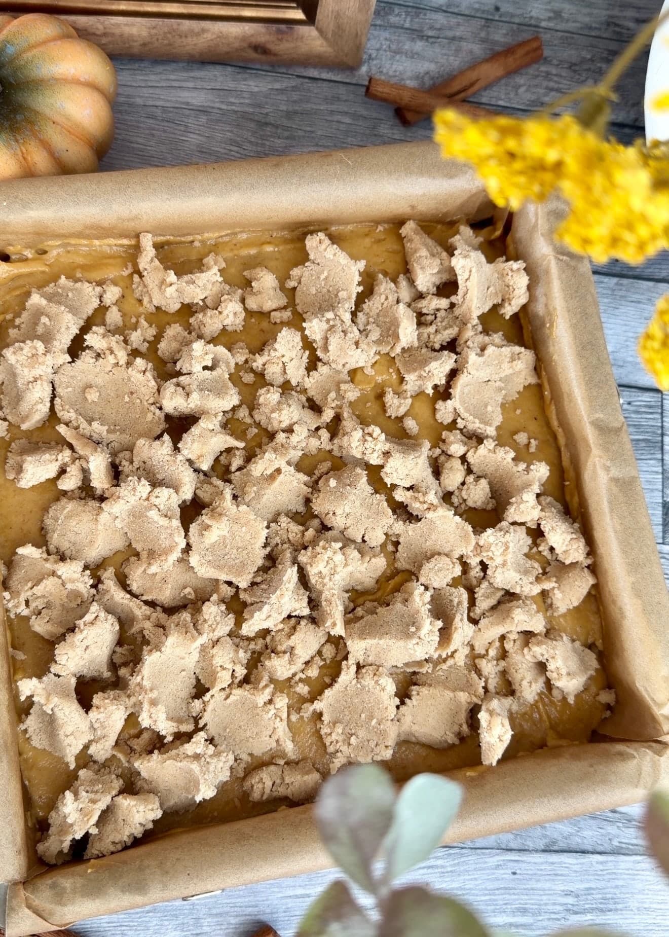 Unbaked pumpkin cake covered with large pale crumble clusters