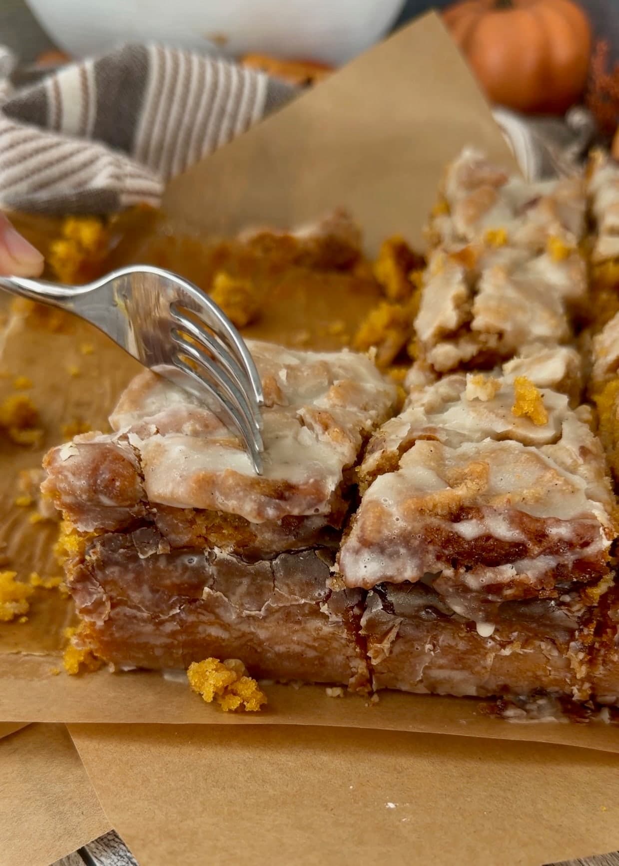 A fork touching the crumble on a cut piece with orange pumpkin crumb behind it