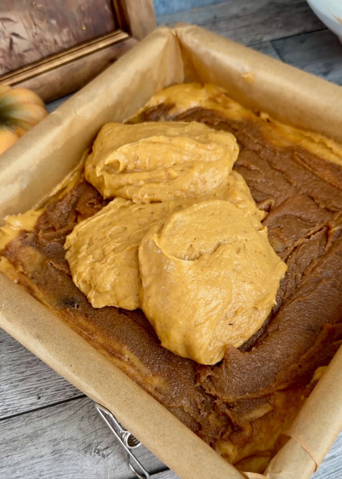 Several spoonfuls of orange batter resting over the cinnamon filling
