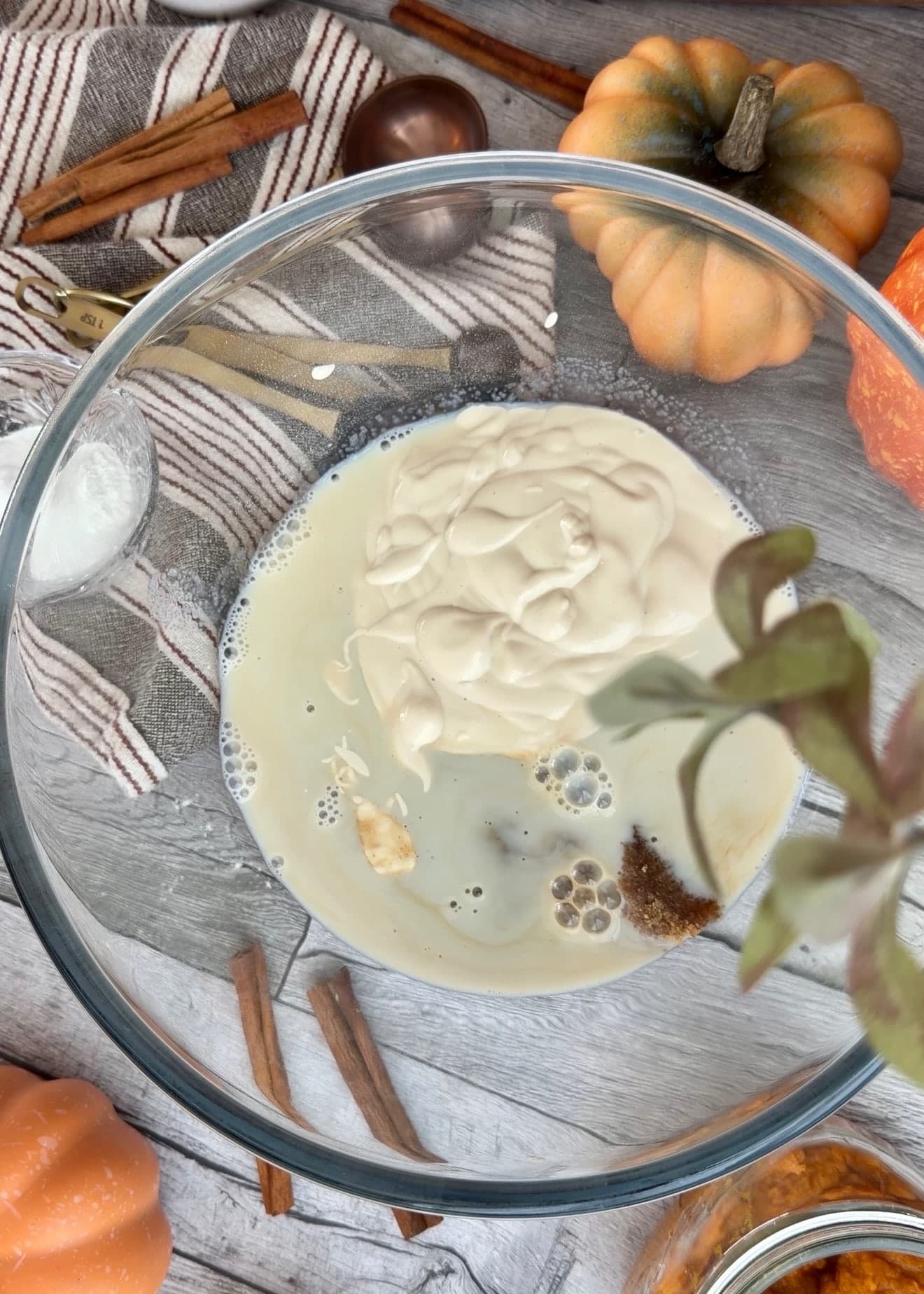 Yogurt, milk, and sugar in a glass mixing bowl before whisking