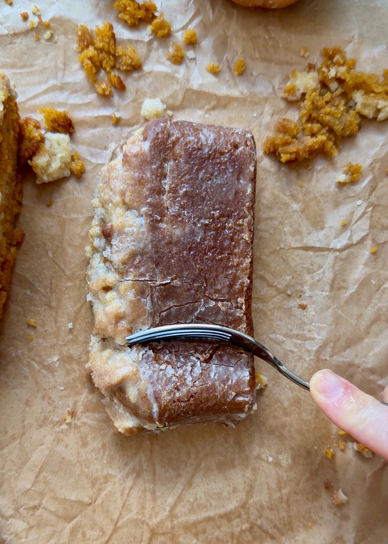 Single slice of glazed pumpkin spice donut loaf on parchment