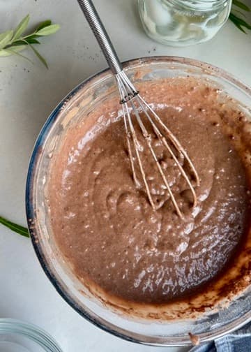 Cocoa-colored batter in a glass bowl with a whisk