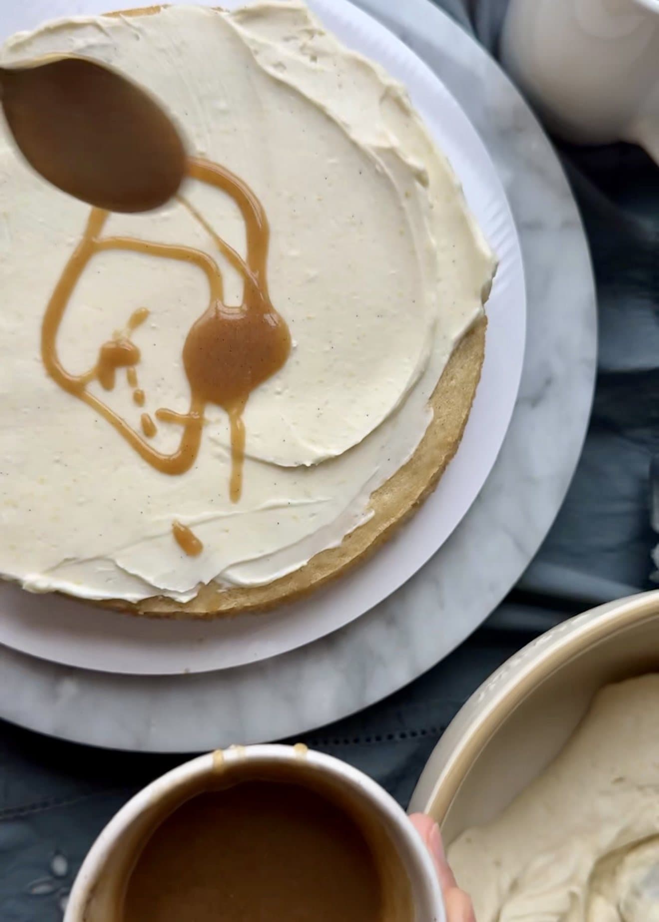 Brown sugar vanilla salted caramel being spooned over cheesecake frosting