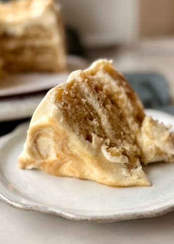 Close view of a slice of salted caramel blondie cheesecake cake showing its soft layers and creamy frosting