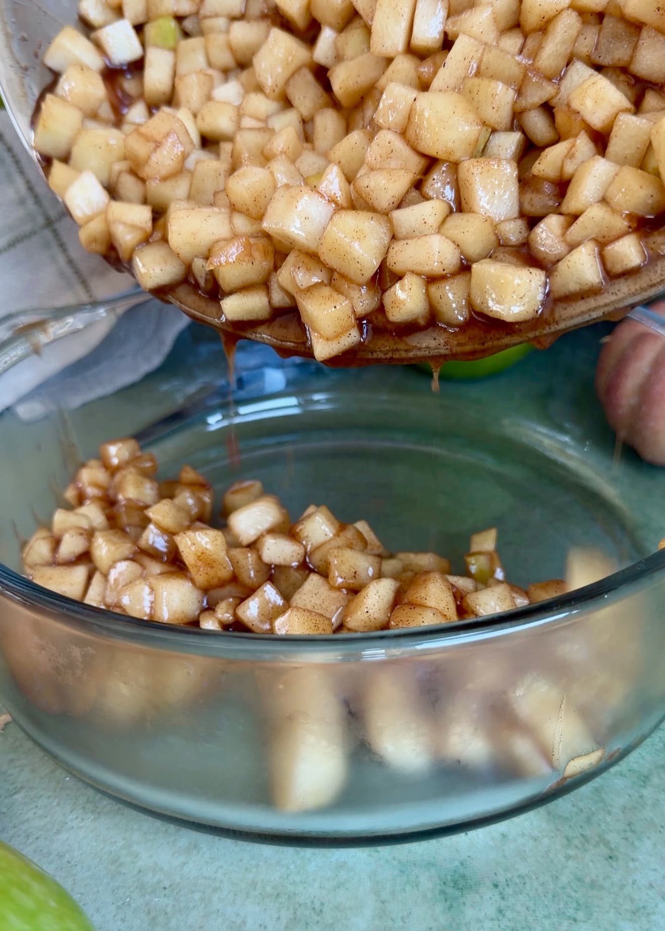 Skillet apple pie filling being transferred to a bowl to cool