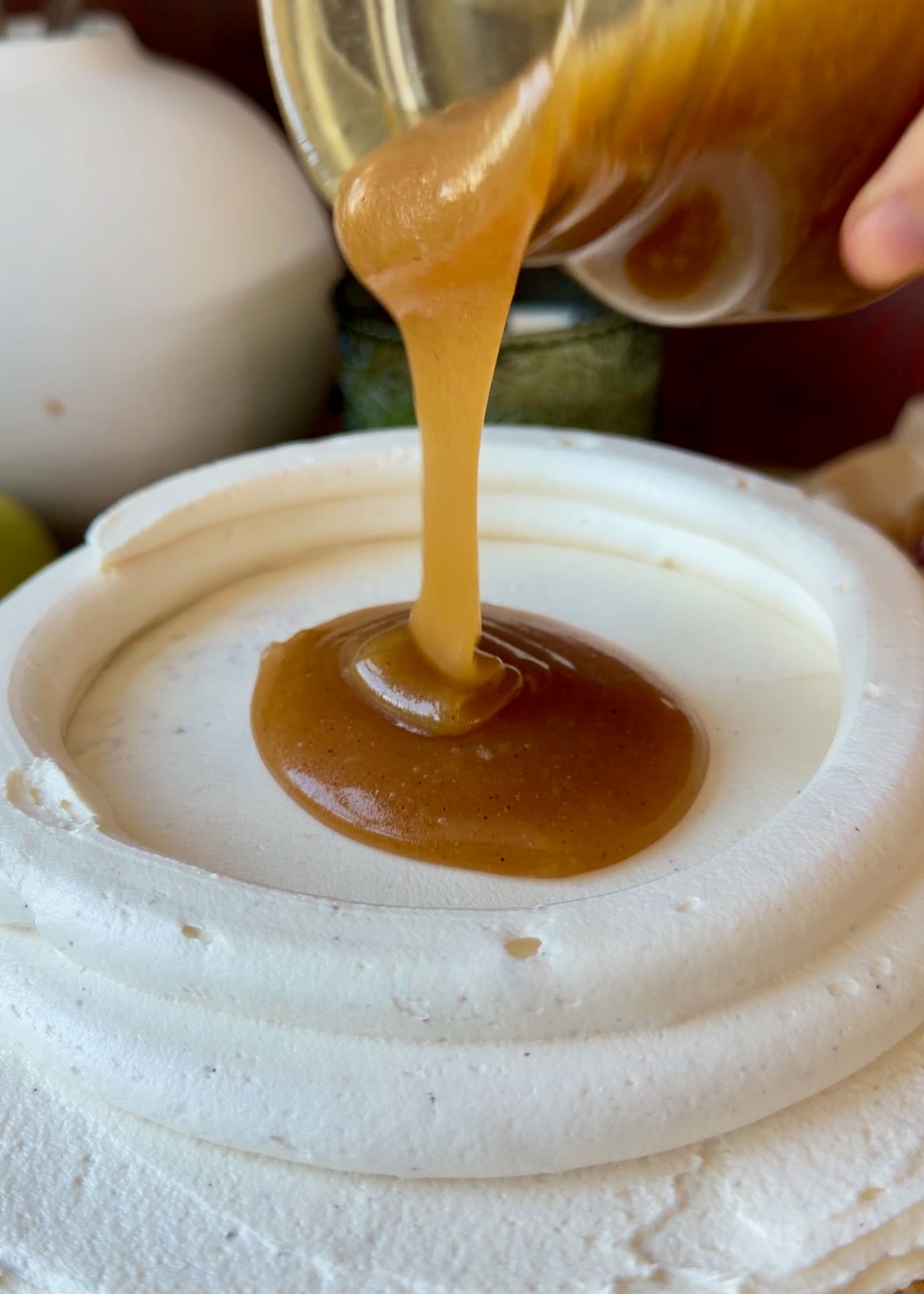 Salted caramel being poured inside a tall vanilla buttercream dam