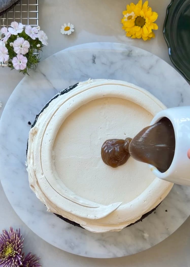 Salted brown sugar caramel being poured inside a vanilla latte buttercream dam