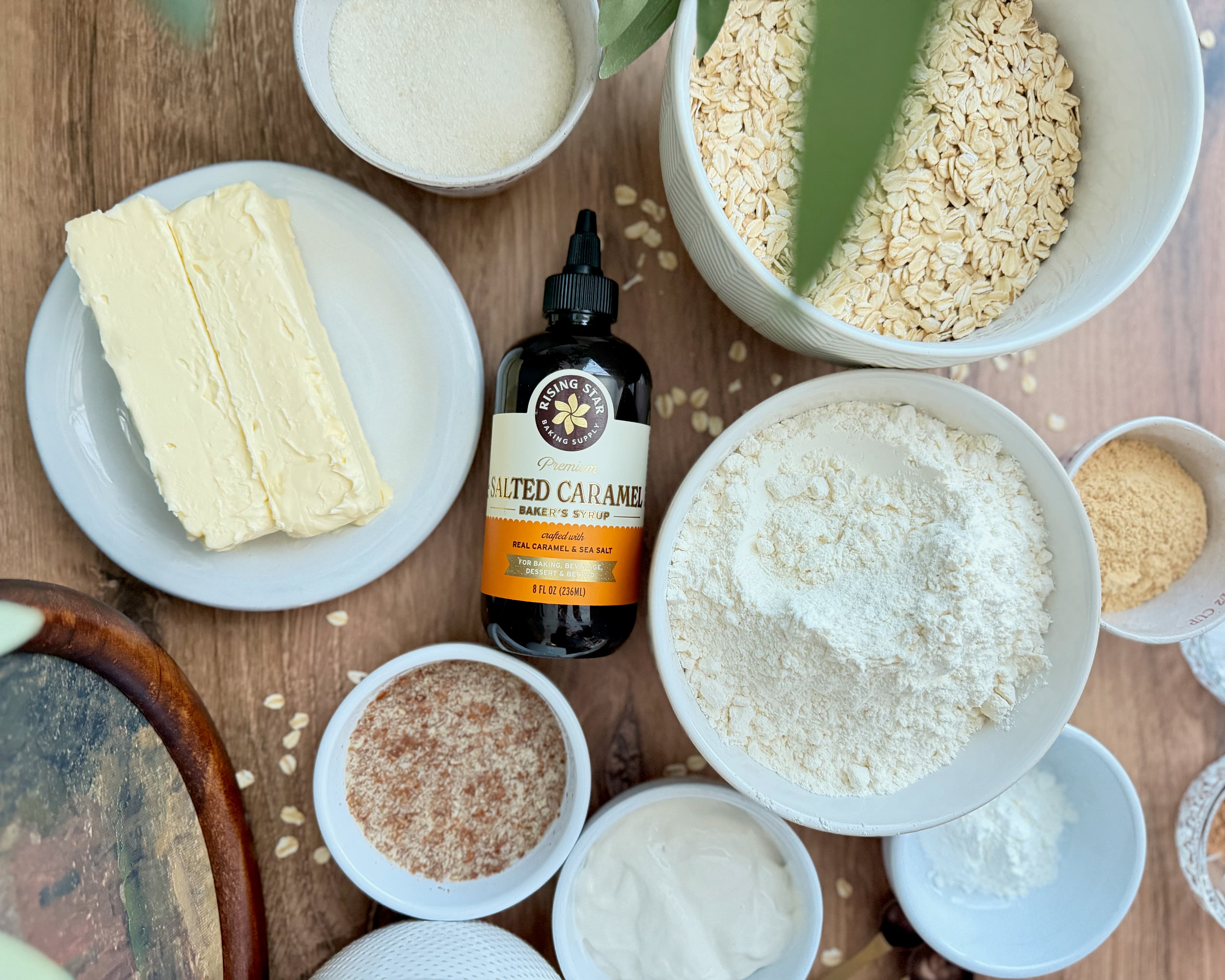 Rolled oats, flour, butter, sugars, yogurt, and flax mixture arranged beside salted caramel syrup