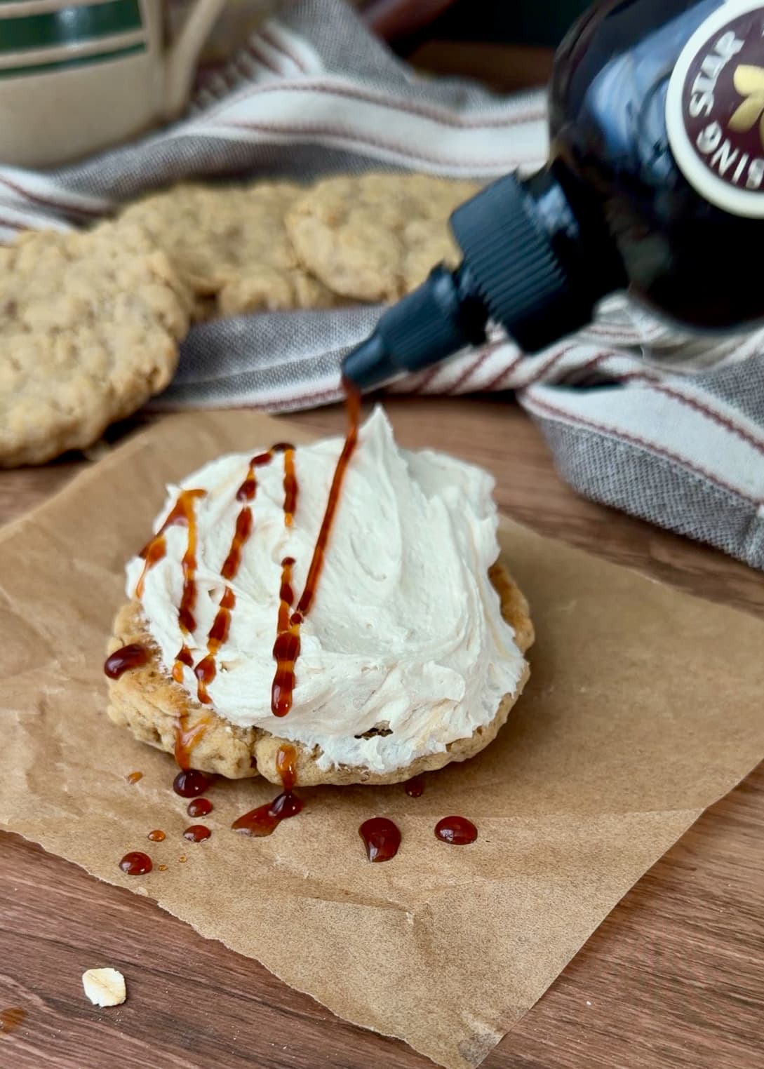 Salted caramel syrup being drizzled over cream on the flat side of an oatmeal cookie