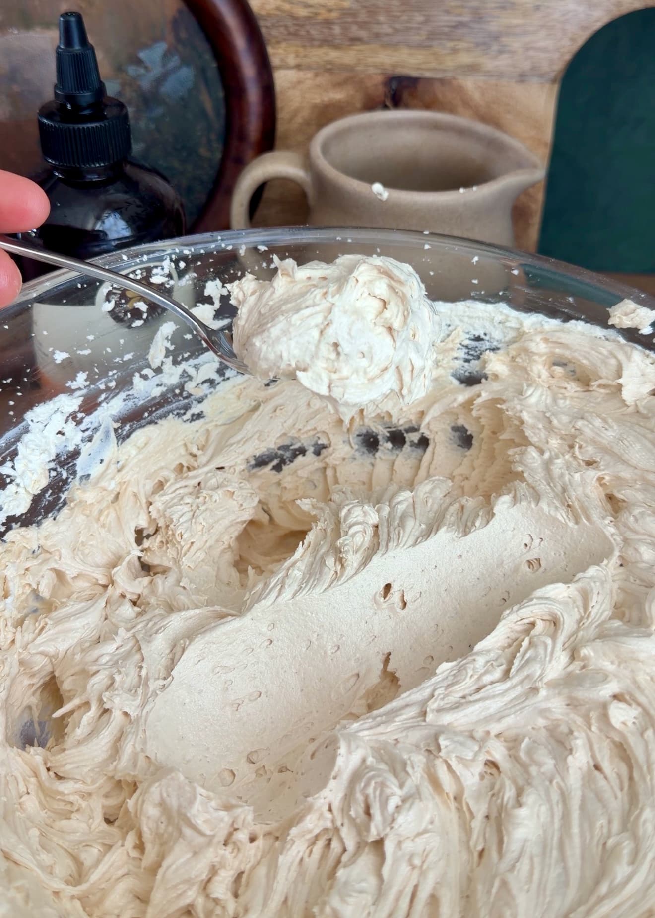 A spoon holding a soft mound of finished cream filling above the mixing bowl