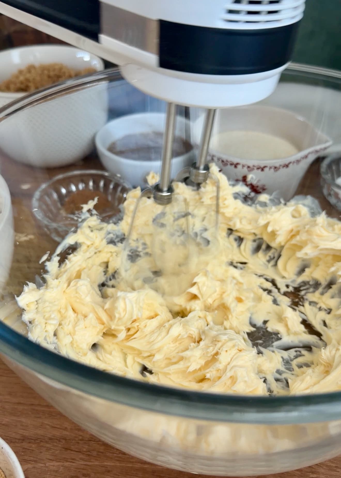 A hand mixer beating softened butter in a glass bowl